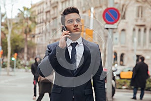 Boy walking with blue suit and calling by phone in city