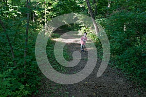 Boy walking on pathway in green open space with mature trees on a sunny day with light clouds at Stroud Preserve