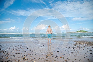 Boy walking towards the water on a beautiful beach day at Coffs Harbour