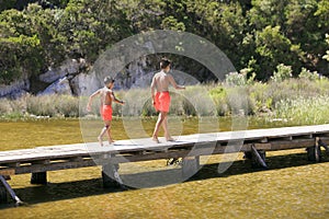Boy walking on a wooden foot bridge on a lake