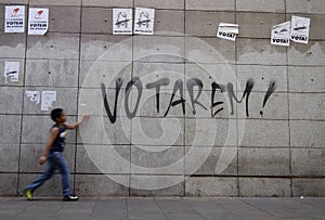 A boy walks in front of a graffiti that says we will vote in Barcelona