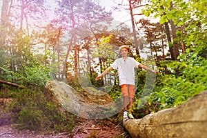 Boy walks over log in the forest balance with hand