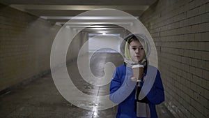 Boy walks through the tunnel in the winter and drinks coffee