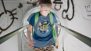 The boy walks under the bridge and climbs into a metal hole. Cool metal corridor.