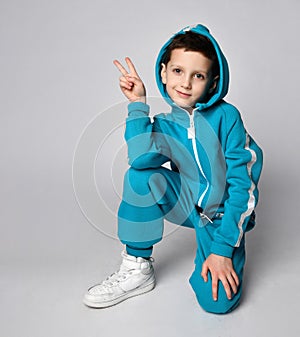 Boy in warm sportswear kneeing gesturing victory