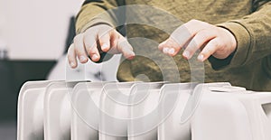 Boy warms hands above the electric radiator photo