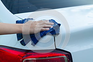 A boy washes a white car with a rag in the summer at the dacha himself