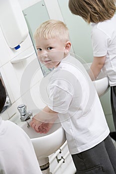 A boy washing his hands in a school bathroom