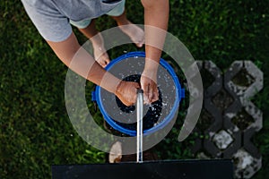 Boy washing his hands with water from a well. Well with a pump for outdoor washing in garden.