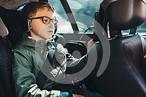 Boy watch a tablet on the car back seat