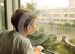 Boy watching the rain through the window