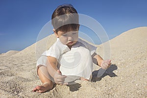 Boy wearing an arabian dress playing in the sand among the dunes