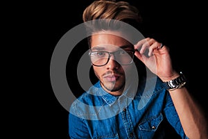 Boy wearing denim posing while fixing his glasses