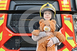 A boy wearing a fireman's helmet near a fire truck.