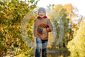 boy wearing leather jacket run in autumn central park in Saint-petersburg, Russia on sunny october day