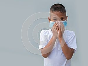 Boy wearing a protective mask And put his hand on his mouth On a gray background