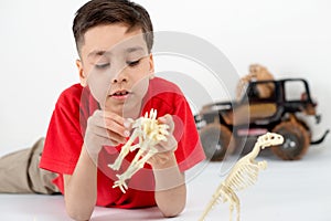 The boy wearing red shirt lies on a floor and plays with toy s