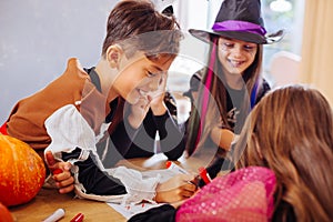 Boy wearing skeleton Halloween costume helping his sister coloring picture