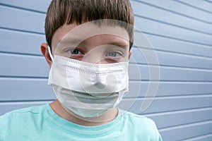 A boy wearing white protective surgical medical mask to prevent infection during epidemia photo
