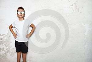 Boy wearing white tshirt, shorts stands on a wall