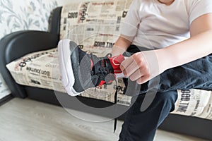 The boy wears running shoes sitting on a sofa in