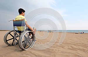 Boy on the wheelchair in the beach in summer