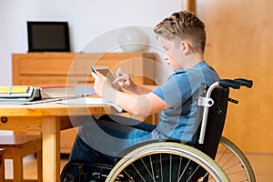 Boy in wheelchair doing homework and using tablet pc