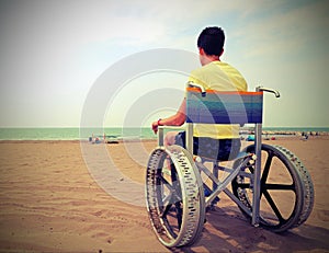 boy on a wheelchair looks at the sea