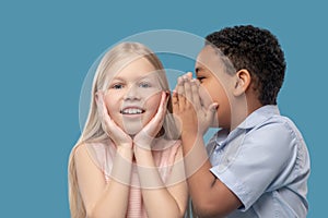 Boy whispering in ear of his surprised girlfriend