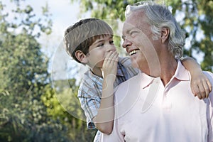 Boy Whispering In Grandfather's Ear