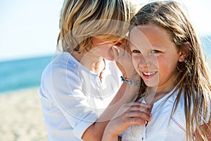 Boy whispering secrets to girl outdoors.