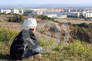 A boy in a white cap is looking on city