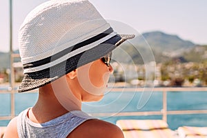 A boy in a white hat looking at the sea. summer