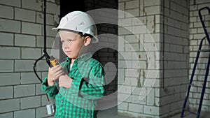 a boy in a white helmet, is playing inspector at a construction site
