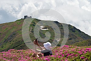 A boy with a white panama on his head sits between rhododendrons with a view of Pip Ivan.