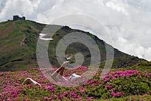 A boy with a white panama on his head sits between rhododendrons with a view of Pip Ivan.