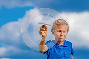 Boy with paper plane against blue sky