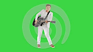 Boy in white playing acoustic guitar and dancing on a Green Screen, Chroma Key.