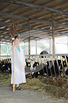 Boy in white robe with broom stands near stall