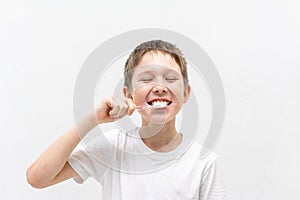 A boy in a white T-shirt is brushing his teeth in the bathroom.