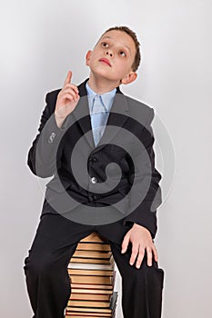 Boy who was visited by the idea, sits on a stack of books with a raised index finger