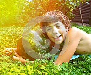 Boy with whole water melon lay on the green grass