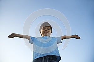 Boy with widely placed hands on background of sky photo