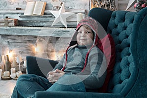 Boy in winter clothes in the chair on holyday background photo