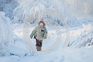 Boy in winter clothes runs on a snowy forest