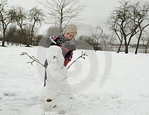 The boy is working diligently sculpts a snowman.