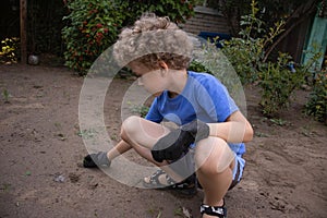 The boy is working in the garden, putting things in order on the garden plot. Teaching children to work. The photo