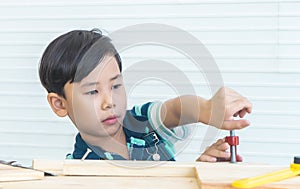 Boy is working out tool on woodwork in workshop