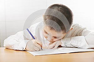 Boy writing bending over copybook