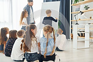 Boy writing on the board. Group of children students in class at school with teacher